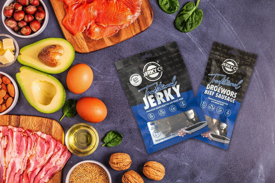 Keto-friendly snack ingredients including beef jerky, droëwors, avocado, eggs, smoked salmon, nuts and olive oil.